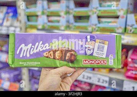 Metaphor of Monopoly game of real estate and brand ownership in supermarket retail chains, Milka MMmax chocolate with whole hazelnuts, green and purpl Stock Photo