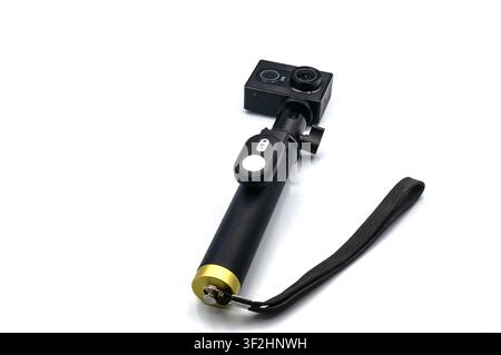 Digital action camera mounted on a handheld monopod with a wireless remote control, against a white background Stock Photo