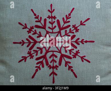 Festive red embroidered snowflake on linen. Ideal for Christmas decor and winter holiday design concepts. Stock Photo
