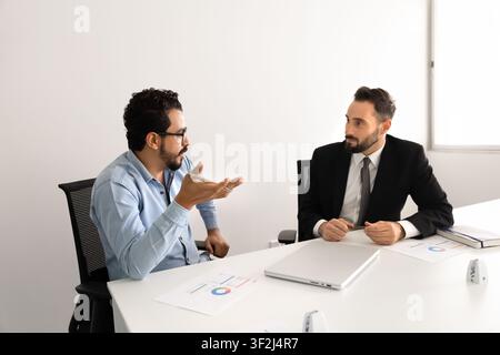 Multiethnic male professionals discussing financial reports in corporate office Stock Photo