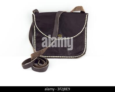 Dark brown leather crossbody bag with white stitching sits elegantly on clean white surface. simple studio setting evokes notions of sophistication an Stock Photo
