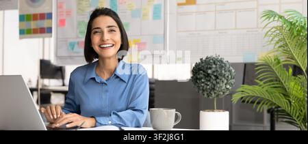 Portrait of female designer working on laptop in creative office Stock Photo