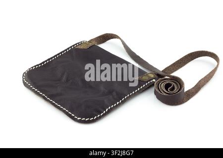 Dark leather crossbody bag with white stitching sits elegantly against clean white backdrop, evoking rustic and minimalist aesthetic. simple design su Stock Photo