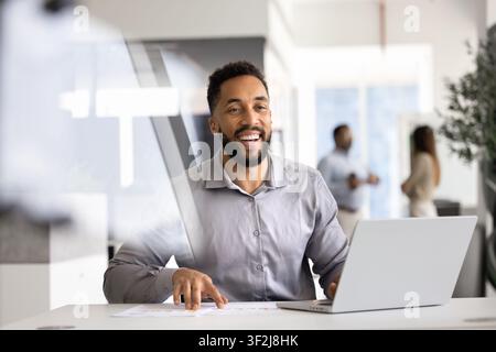 Laughing businessman working at office desk with laptop Stock Photo