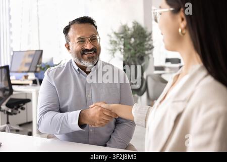 Mature Indian HR manager shaking hands with female applicant Stock Photo