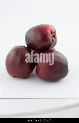 Three vibrant red apples create pleasing still life arrangement on clean white surface. neutral studio setting evokes feelings of freshness and simpli Stock Photo
