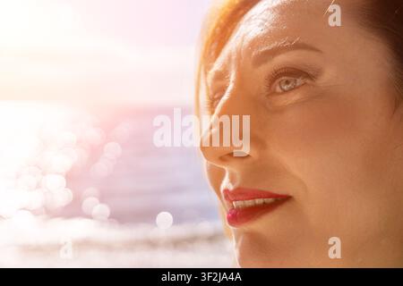Woman portrait sunset close up profile of a smiling middle aged woman looking at the ocean during golden hour Stock Photo