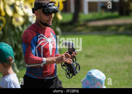 Kyiv, Ukraine - July 17, 2026: An FPV drone pilot wearing video goggles prepares a quadcopter for flight while holding a remote controller during an o Stock Photo