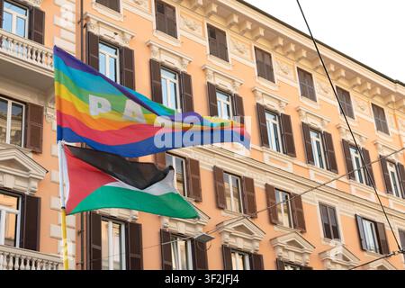 ROME, ITALY - JULY 18, 2026: Low angle view of Palestinian and rainbow peace flags waving in the wind against the facade of a classic orange residenti Stock Photo