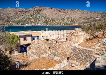 Historic stone houses and ruins of the former leper colony on Spinalonga overlook the blue sea and arid mountains near Elounda on Crete, Greece. Stock Photo