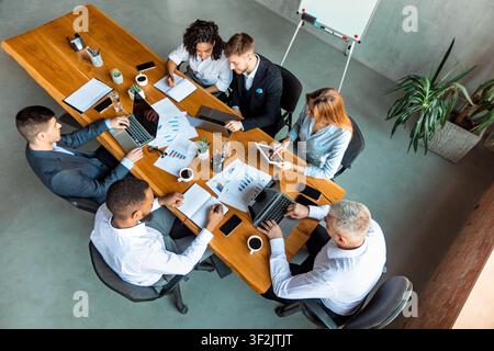 Coworkers Working Sitting At One Desk Using Gadgets In Office Stock Photo