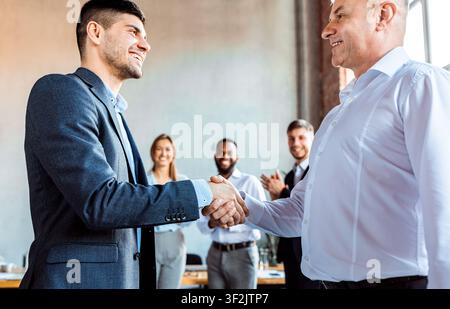 Two Entrepreneurs Shaking Hands During Business Meeting Standing In Office Stock Photo