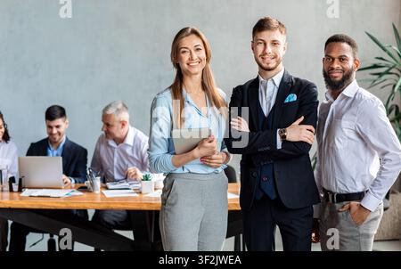 Three Business Partners Standing Smiling To Camera In Modern Office Stock Photo