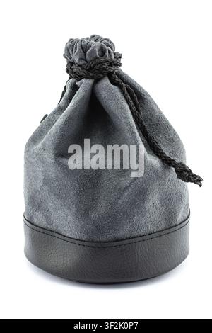 Sleek dark gray suede drawstring bag rests on pristine white surface within calm studio setting. bag's black leather base provides sophisticated contr Stock Photo