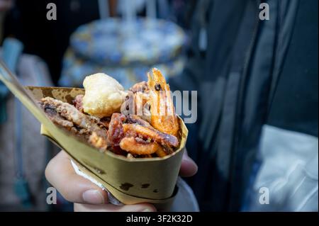 Naples, italy. December 29, 2024. Hand holding a traditional cuoppo from naples, italy, filled with mixed fried seafood and savory snacks Stock Photo