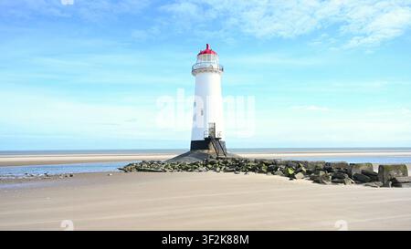 TALACRE, WALES - JUL 05, 2024: The Point of Ayr Lighthouse stands on a sandy beach surrounded by rocks during low tide in Talacre, North Wales. Stock Photo