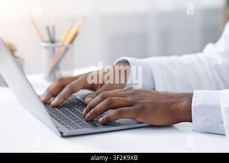 Close up of black doctor hands typing on laptop Stock Photo