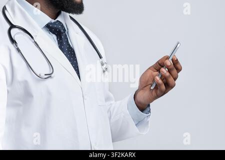 Cropped of black therapist holding mobile phone, white background Stock Photo