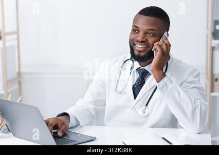 Friendly doctor asking about patients health, using mobile phone Stock Photo