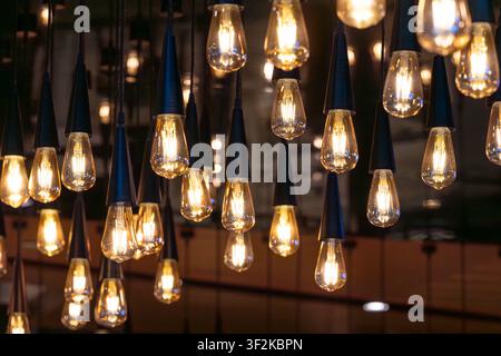 Lots of decorative soft light bulbs hanging from the ceiling in a dark room. Stock Photo