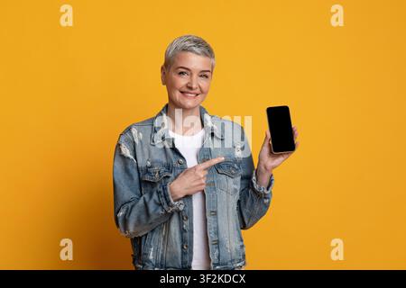 Great App. Smiling Mature Lady Pointing At Smartphone With Black Screen Stock Photo