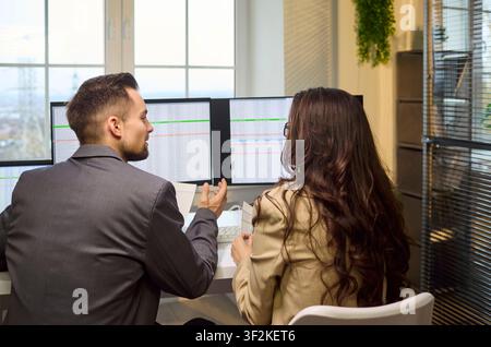 Business colleagues discussing financial data on screens in contemporary office Stock Photo