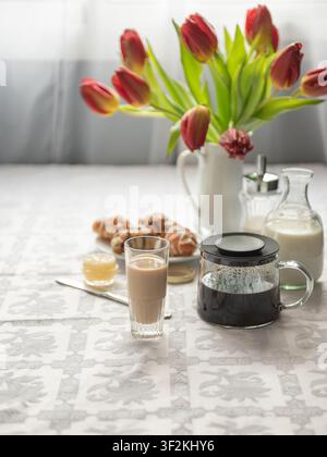 Morning coffee with milk, croissants and red tulips on table. Stock Photo