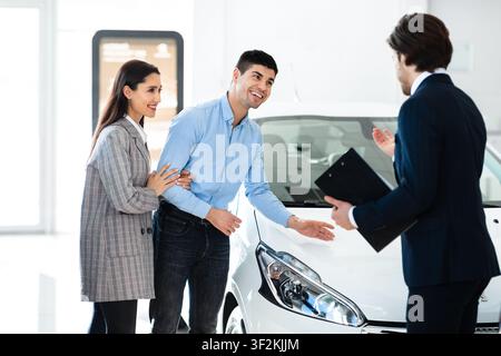 Couple Choosing And Checking Car With Manager In Rental Service Stock Photo