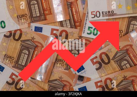 A red upward-trending arrow against a background of fifty-euro banknotes Stock Photo