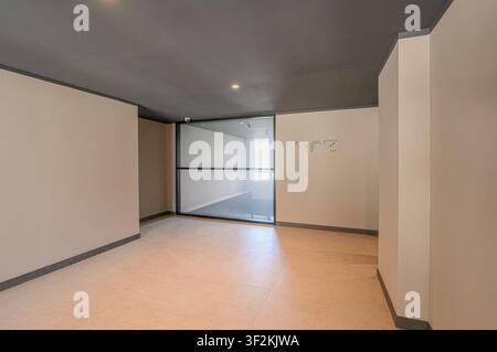 interior shot features a neutral-toned room with a gray ceiling. A large glass partition separates the space, offering a view into another room. Minim Stock Photo