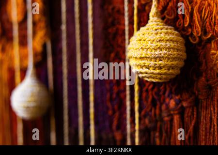 Close-up of handmade woven tapestry wall decor with yarn texture and knitted elements Stock Photo