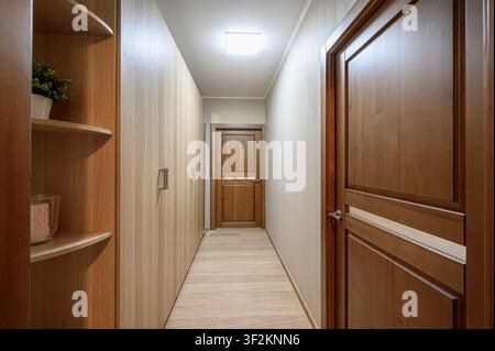 Hallway with wooden doors and closets, lit by a ceiling light Stock Photo