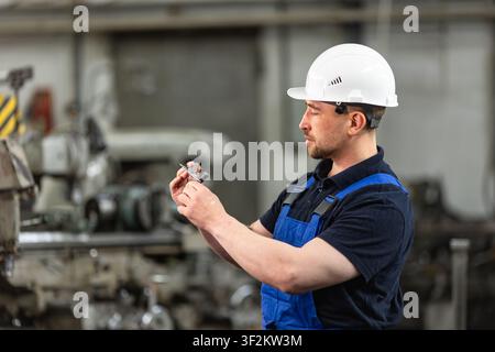 Industrial engineer inspecting precision metal part at manufacturing factory Stock Photo