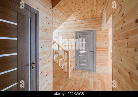 hallway or room with wood paneling, stairs, and two modern doors, creating a warm and inviting rustic yet modern space Stock Photo