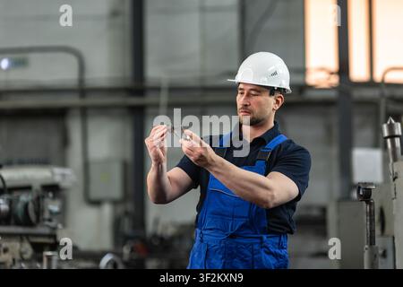Industrial worker measuring metal part with caliper at manufacturing factory Stock Photo