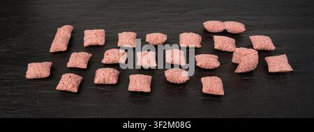 Fruit pillows, strawberry corn pads for breakfast isolated. Pink crispy corn flakes with milk and berry filling on white background Stock Photo