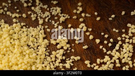 Couscous macro textured background. Dry cuscus pattern, raw kuskus wallpaper, uncooked cous cous or semolina granules close up with selective focus Stock Photo