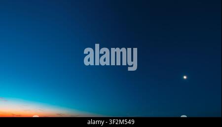 minimalist and smooth clear sky at sunset showing a beautiful color gradient from dark teal and deep blue to bright orange and yellow at the bottom Stock Photo