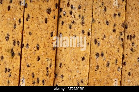 Crunchy gluten free crispbread pattern with various seeds and cheese. Whole grain wheat crisp bread or cracker with sesame macro textured background Stock Photo
