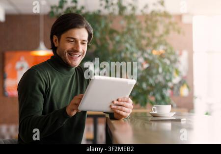 Joyful businessman using digital tablet at modern cafe Stock Photo