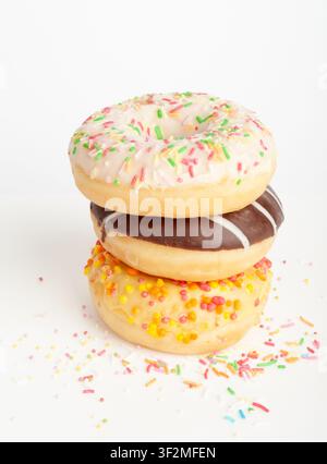 Doughnuts Pile Isolated, Chocolate Brown, Yellow and Pink Donuts, Donuts Stack with Multicolored Sprinkles, Doughnuts on White Background Stock Photo