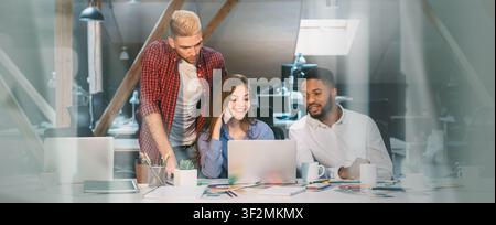 Diverse Team Collaborating On Laptop In Office, Focused Business Concept Stock Photo