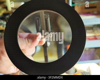 Magnifying glass inspecting a wood screw in a workshop. Close-up of hardware under magnification, concept of precision, quality control, repair, craft Stock Photo