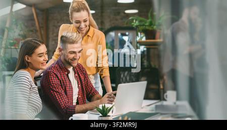 Three Young Professionals Smiling And Collaborating In Office, Business Concept Stock Photo