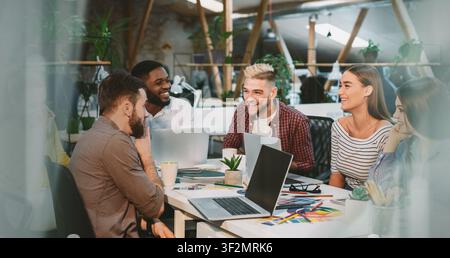 Diverse Group Of Young Professionals Collaborating And Discussing Ideas In Modern Office, Business Concept Stock Photo