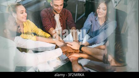 Diverse Group Of Young Adults Collaborating And Stacking Hands In Office, Business Concept Stock Photo