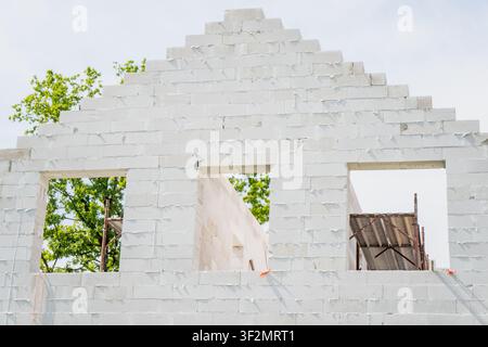 Aerated concrete blockwork forming a stepped gable wall structure on a residential building site, representing masonry craftsmanship and engineering w Stock Photo