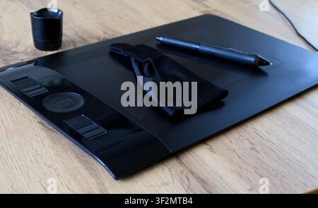 Digital stylus and a black drawing glove rest on a black graphics tablet. Digital illustration process concept. Stock Photo