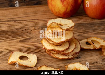 Dry apple slices stack on wood table. Dried apple chips, healthy fruit snack side view, dehydrated gourmet rings, crunch pitted sweet pear chips on ru Stock Photo