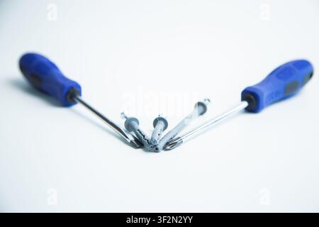 Close-up of two hands in work gloves holding screwdrivers against a white background. Concept of Stock Photo